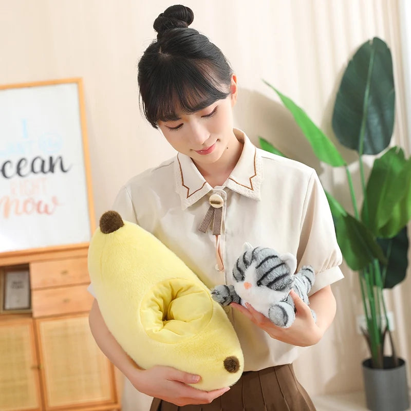 Woman holding a kawaii plush avocado and a small animal toy in a room with a plant and framed picture.