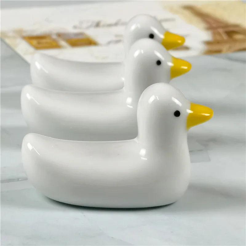 Three duck shaped kawaii chopstick holders sitting on a table