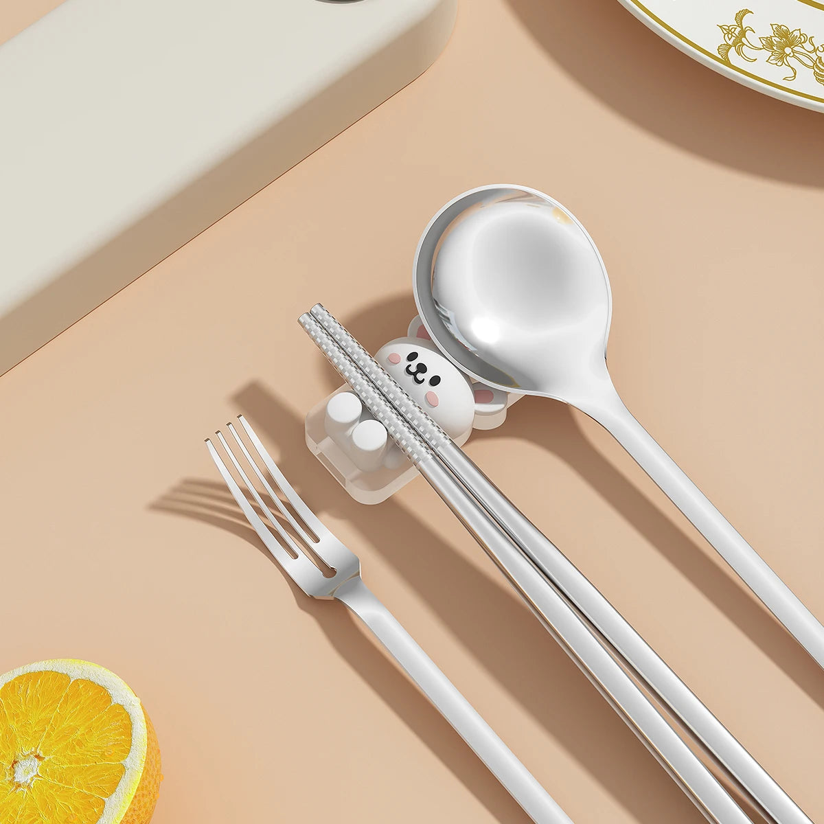 Kawaii utensils on a beige surface with a lemon wedge and small container.