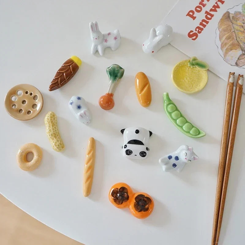 Collection of small ceramic food kawaii chopstick holders and animals on a white surface with chopsticks.