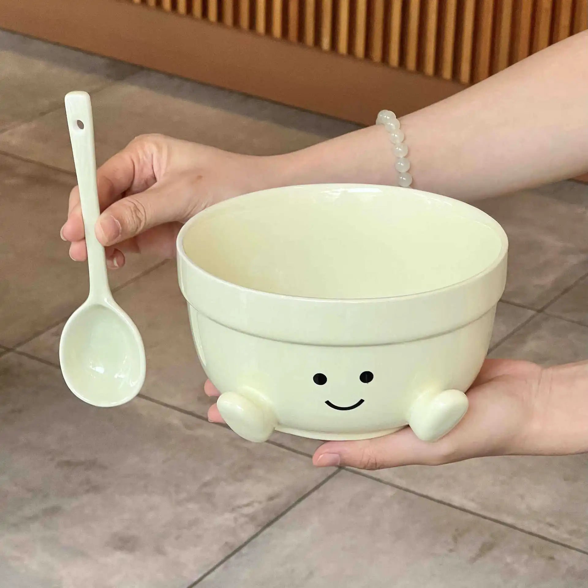 Person holding a white kawaii bowl with a smiley face design and a matching spoon.