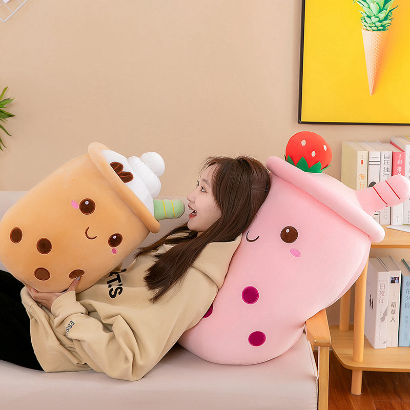 Person sitting on a couch with two large, cute kawaii plush toys resembling ice cream and a strawberry.