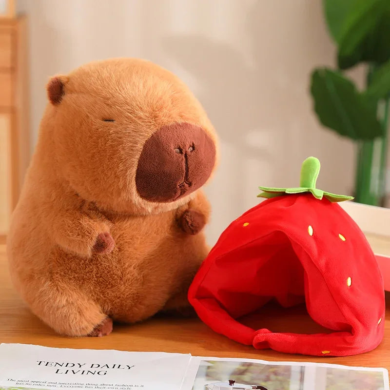 Kawaii plush bear toy next to a red strawberry-shaped pet bed on a table.