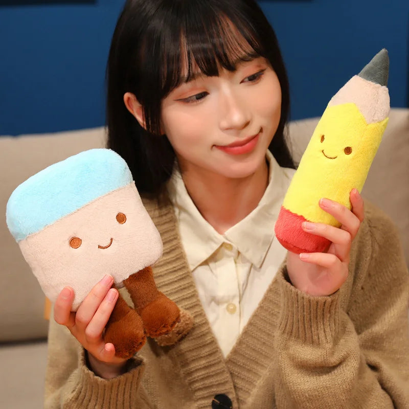 Person holding two kawaii plush toys resembling a person with blue hair and a pencil.