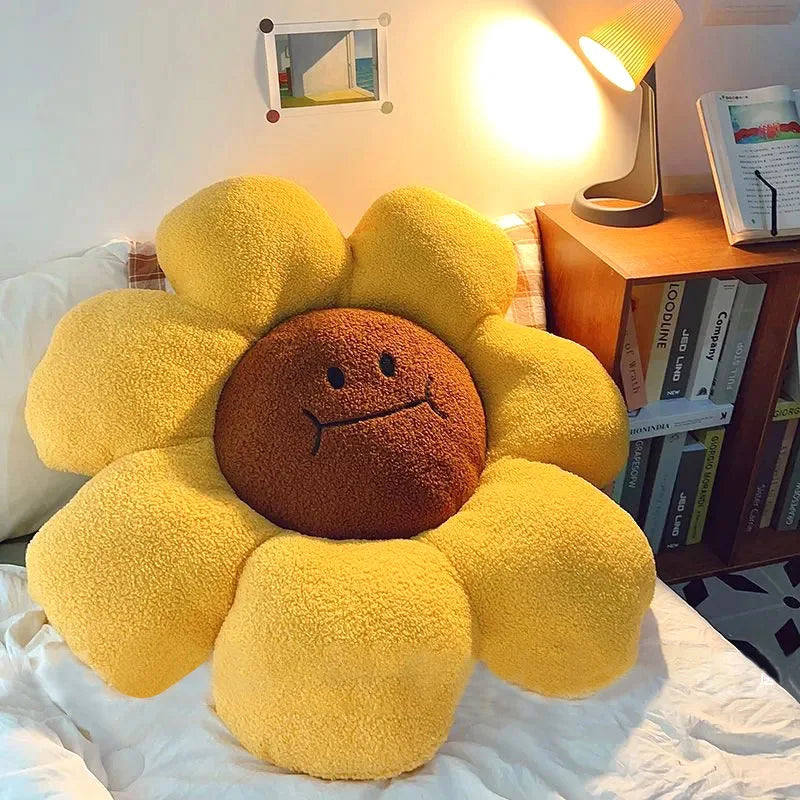 Yellow sunflower-shaped kawaii pillow on a bed with a lamp and books in the background