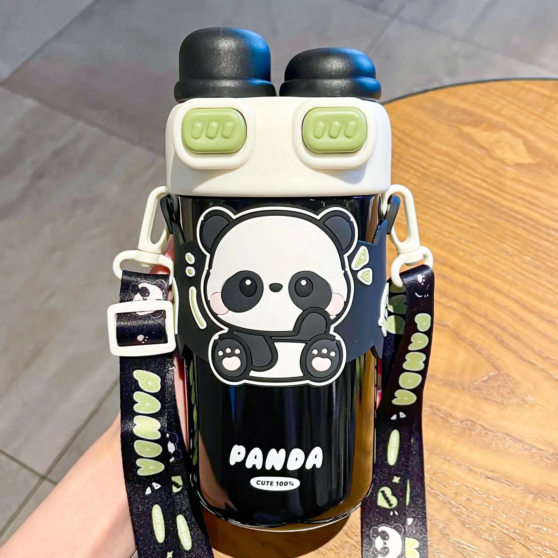 Black kawaii water bottle with panda design and green accents on a wooden surface