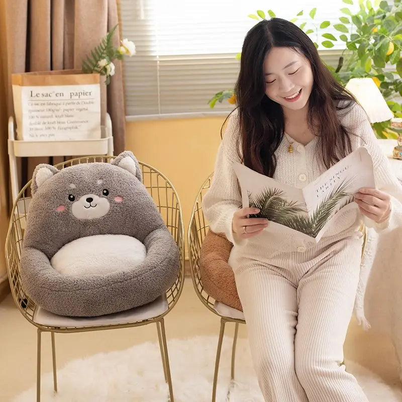 Woman sitting on a chair with a bear-shaped kawaii cushion, reading a magazine in a cozy room.