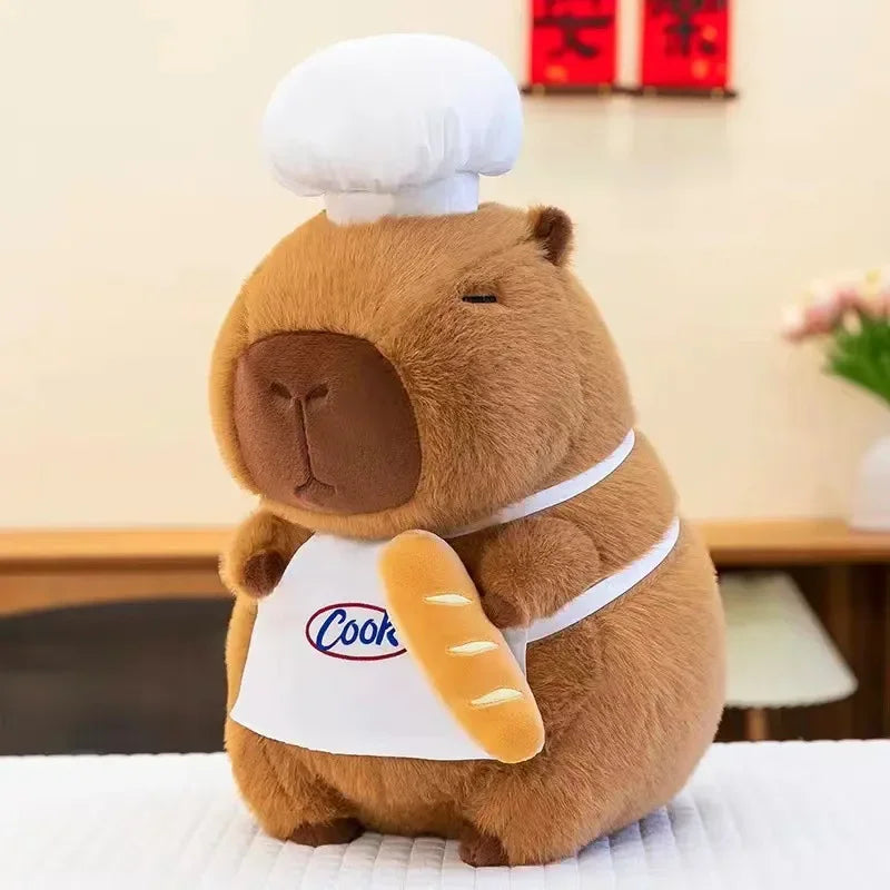 Kawaii plush toy bear wearing a chef's hat and holding a bread roll with 'Cook' written on it, on a light-colored surface.