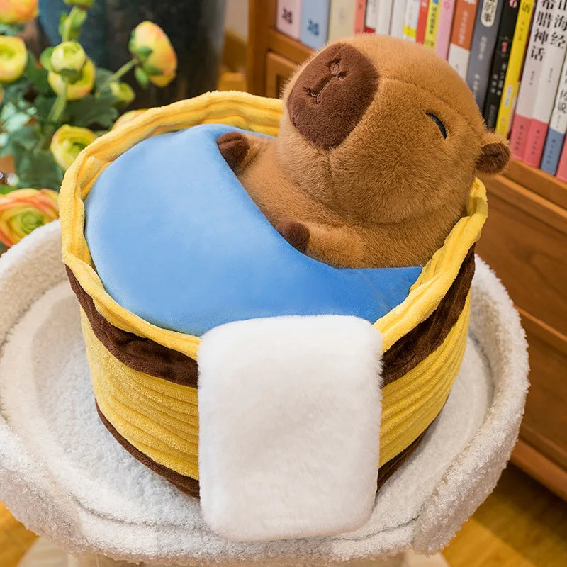 Kawaii plush toy resembling a seal in a basket with a blue cushion, on a white surface with books in the background.