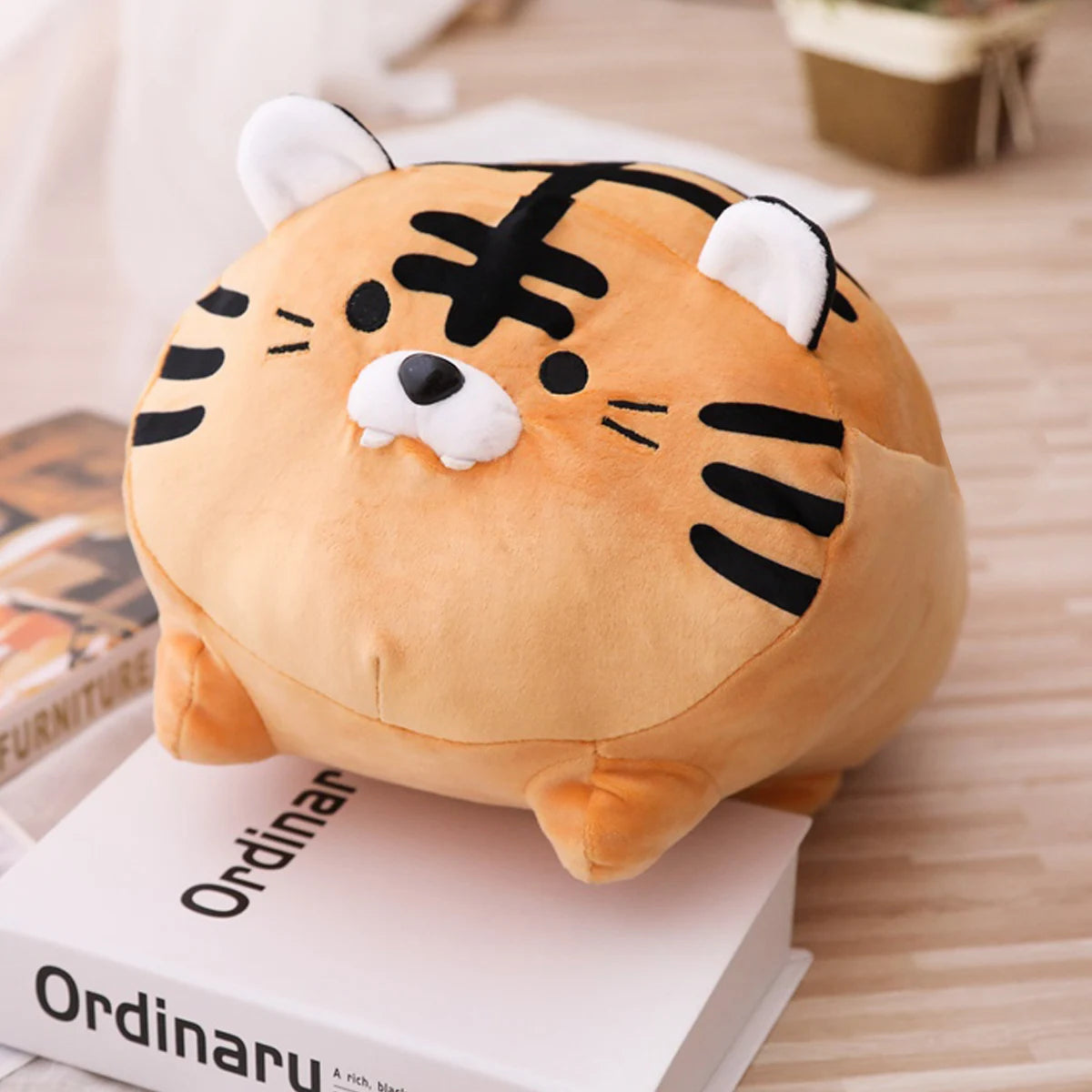 Kawaii plush tiger toy on a book with a blurred background