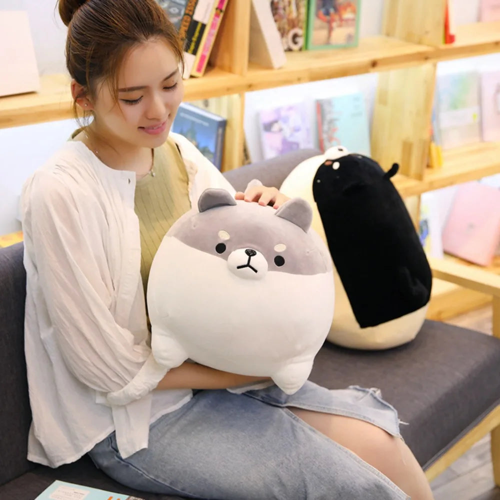 Woman holding a large plush kawaii toy in a cozy room with bookshelves.