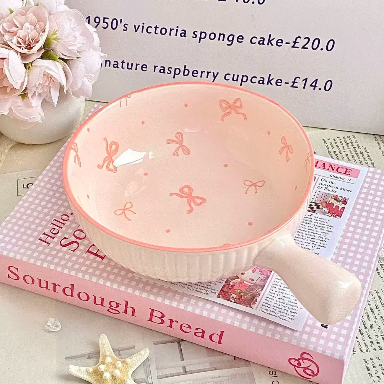 Pink ceramic kawaii ramen bowl with bow pattern on a book with a newspaper underneath