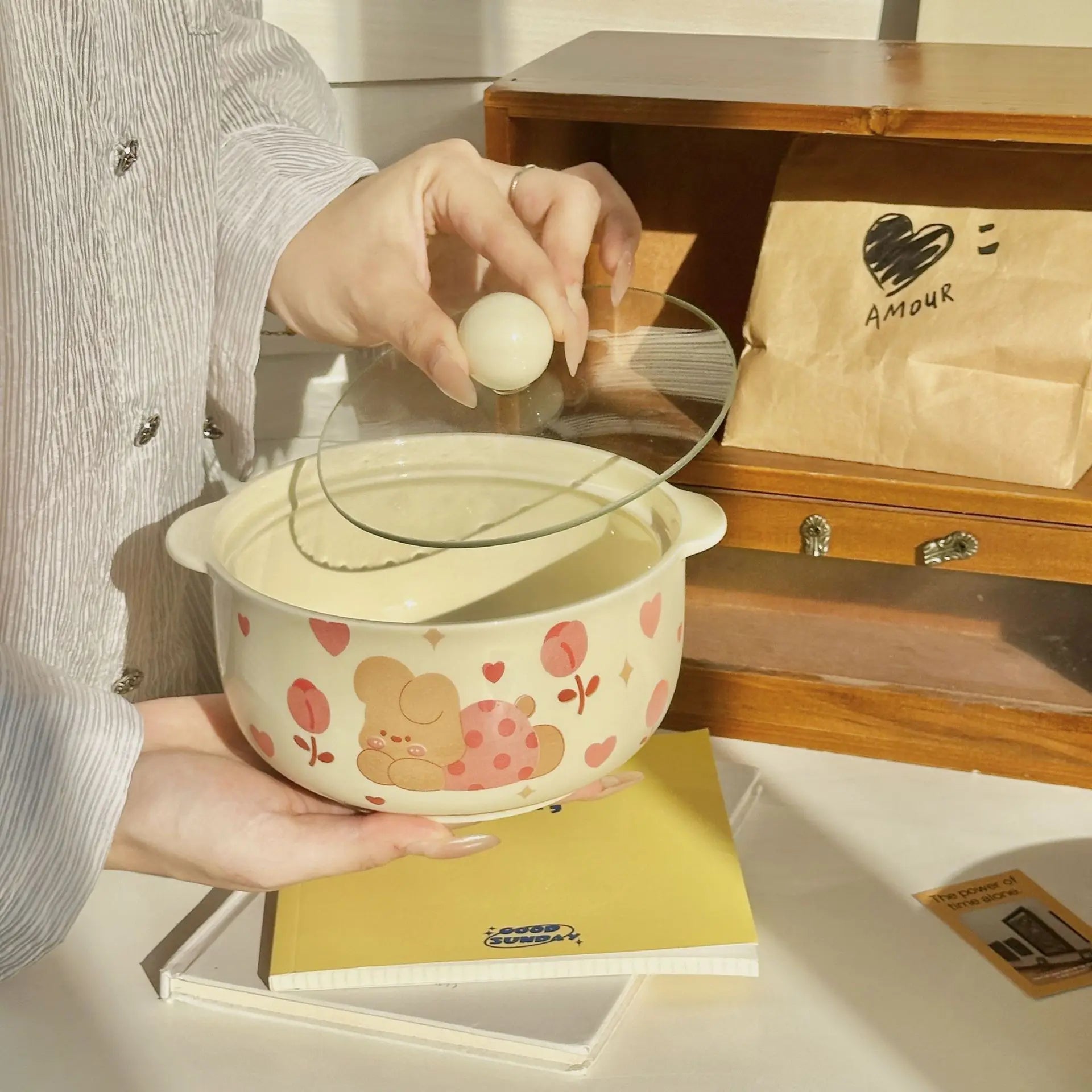 Person holding a ceramic kawaii ramen bowl with a bear design, placing an egg inside.