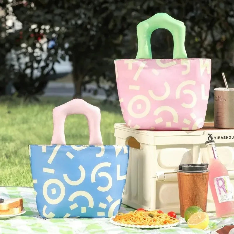 Two patterned kawaii bags on a picnic setup with food and drinks.