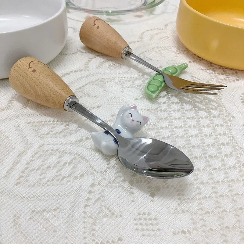 Spoon and fork with wooden kawaii chopstick holders like cats on a textured surface.