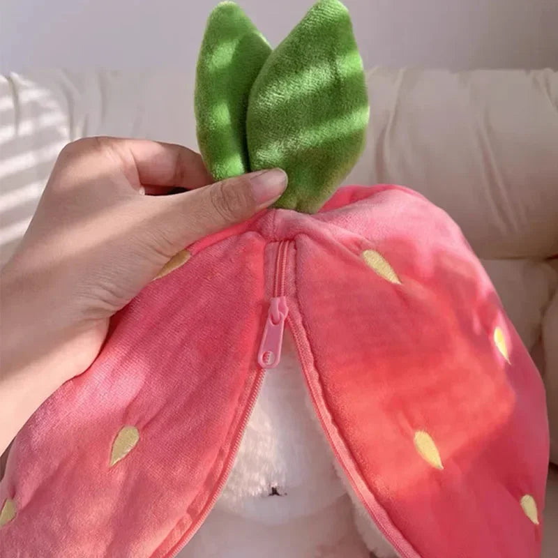 Hand holding a pink plush kawaii toy with green ears against a neutral background