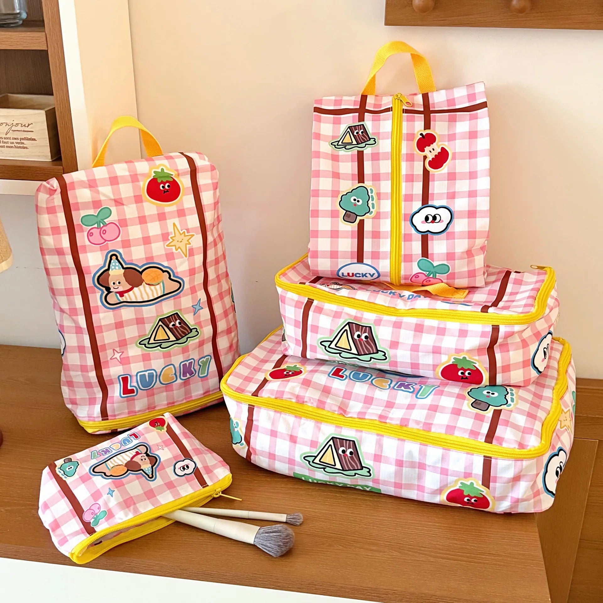 Set of pink checkered bags with Kawaii cartoon designs on a wooden surface