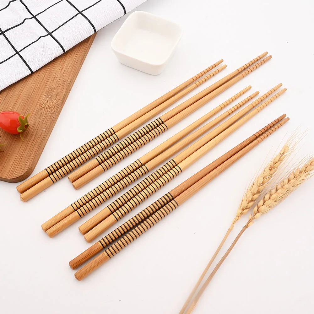 Set of wooden kawaii chopsticks on a white surface with a wooden board and small bowl in the background.