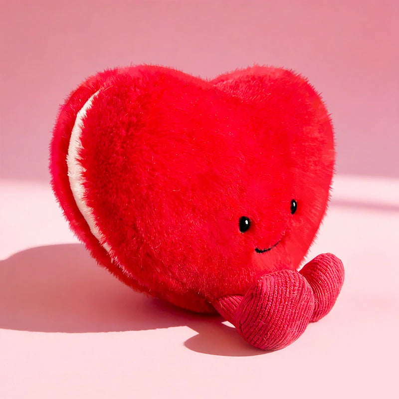 Red heart-shaped kawaii plush toy with a smiling face on a pink background