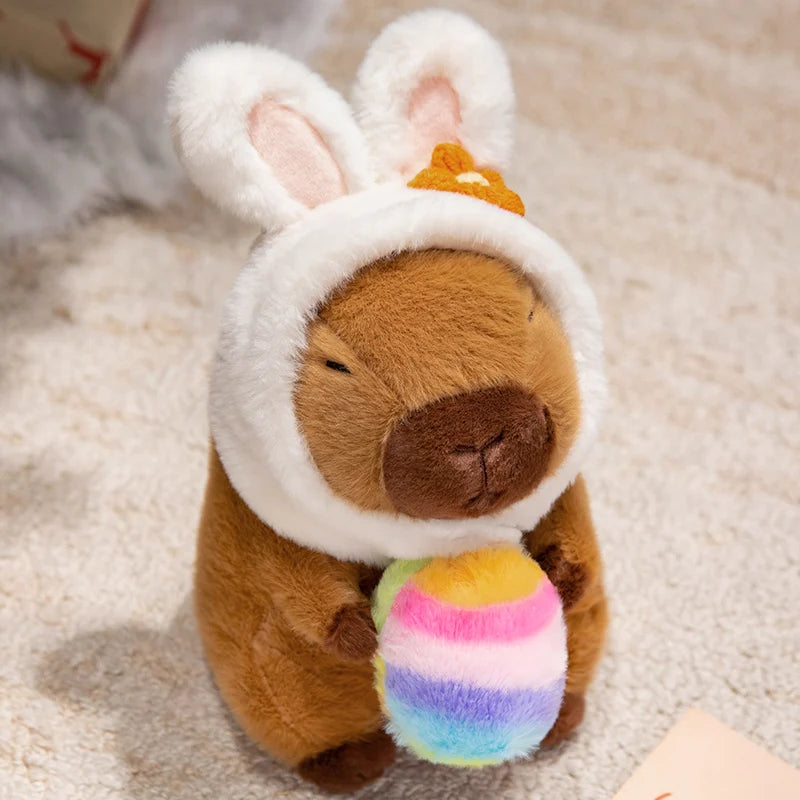 Kawaii plush toy resembling a bear with bunny ears and a rainbow egg on a soft surface