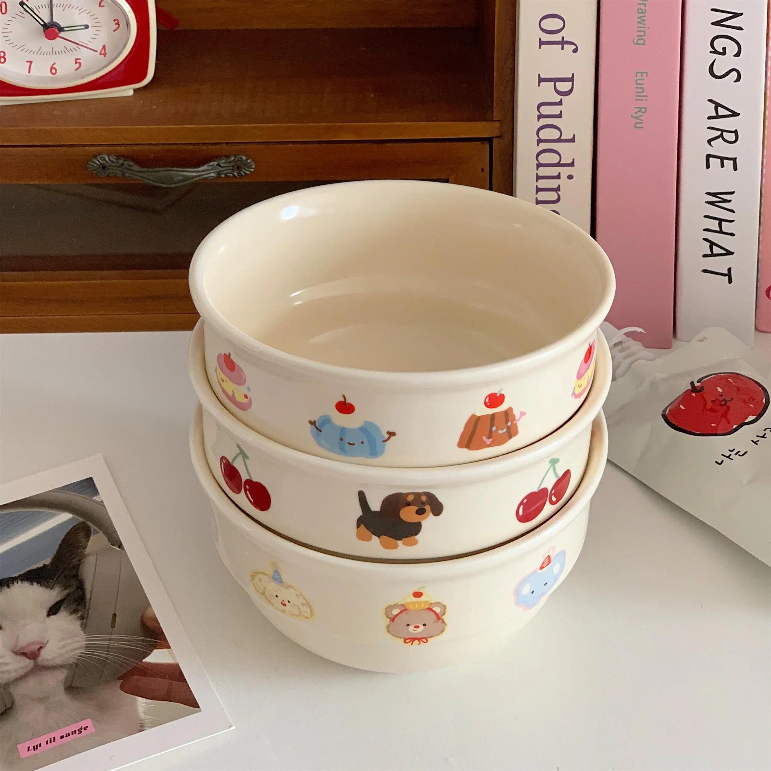 Set of three ceramic kawaii ramen bowls with cute illustrations on a wooden shelf.