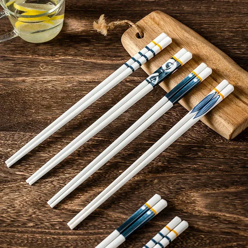 Set of white kawaii chopsticks with blue and gold decorative ends on a wooden surface.