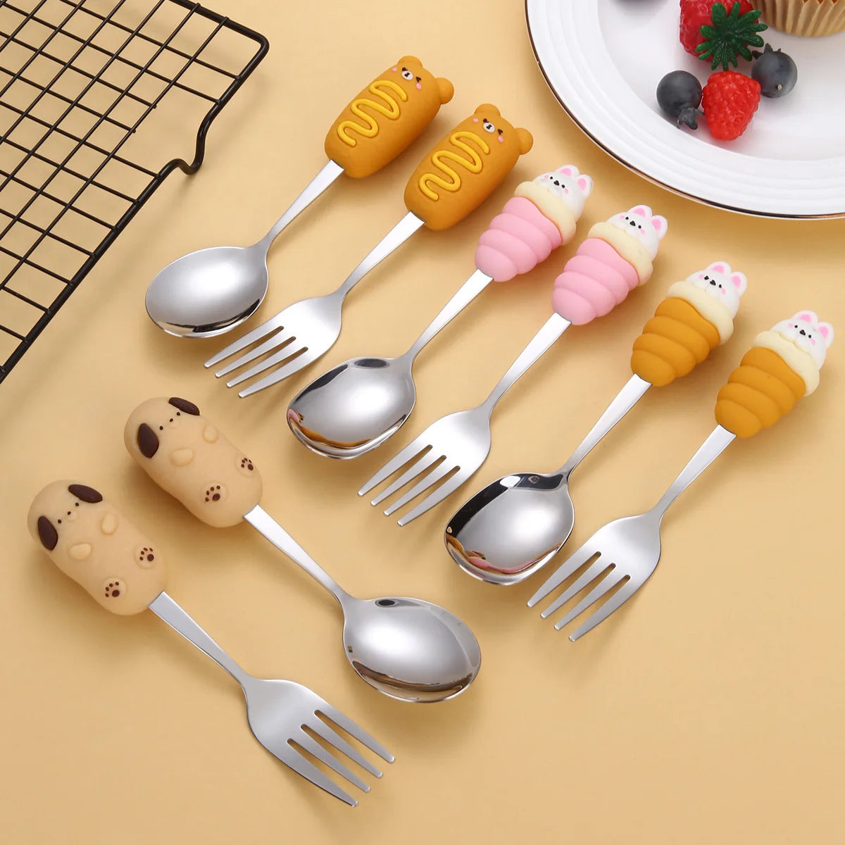 Set of silver kawaii utensils with cartoon-shaped handles on a beige background