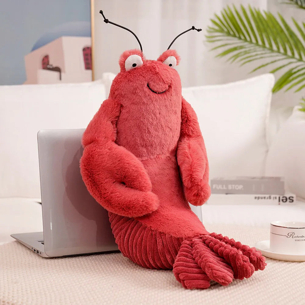 Plush lobster kawaii toy on a couch next to a laptop