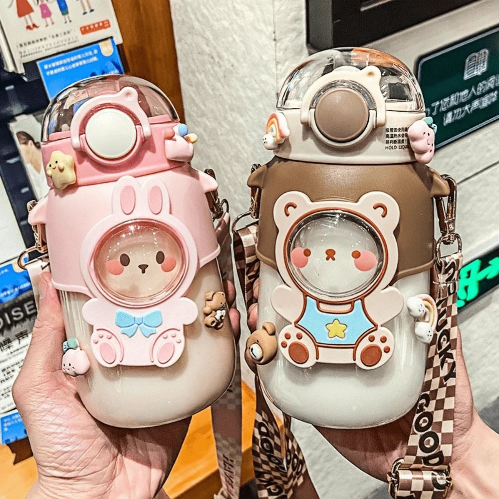 Two cute cartoon-style kawaii water bottles held by a person with a blurred background.