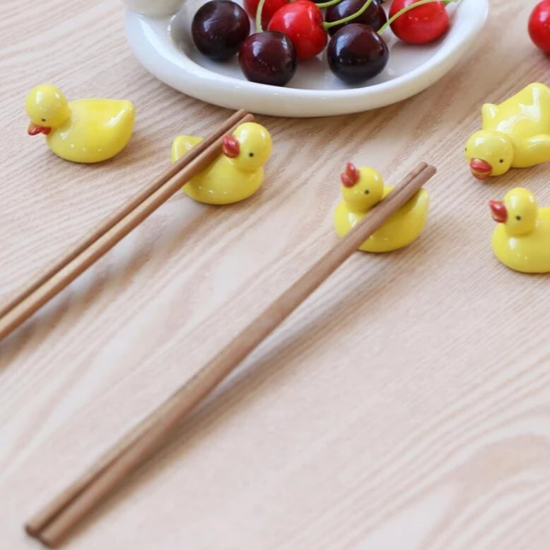 A group of yellow duck kawaii chopstick holders on a table