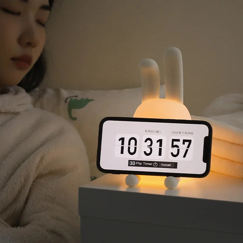 Kawaii night light with rabbit design on a nightstand next to a person in bed