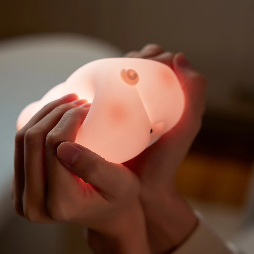Hand holding a glowing pink elephant-shaped kawaii night light against a blurred background