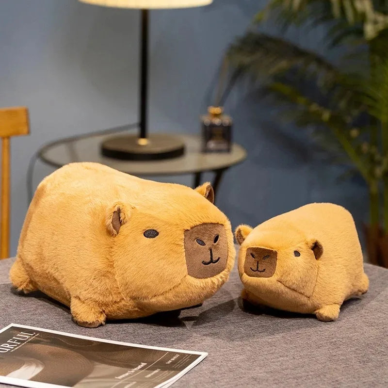 Two kawaii plush guinea pigs on a table with a magazine and plant in the background.