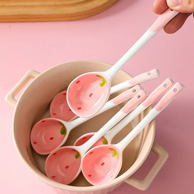 Set of ceramic kawaii spoons with strawberry design in a bowl on a pink background