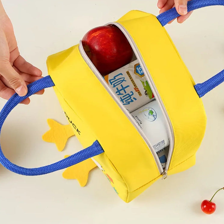 Yellow lunch kawaii bag with blue handle containing an apple and a bottle, held by hands on a light background.