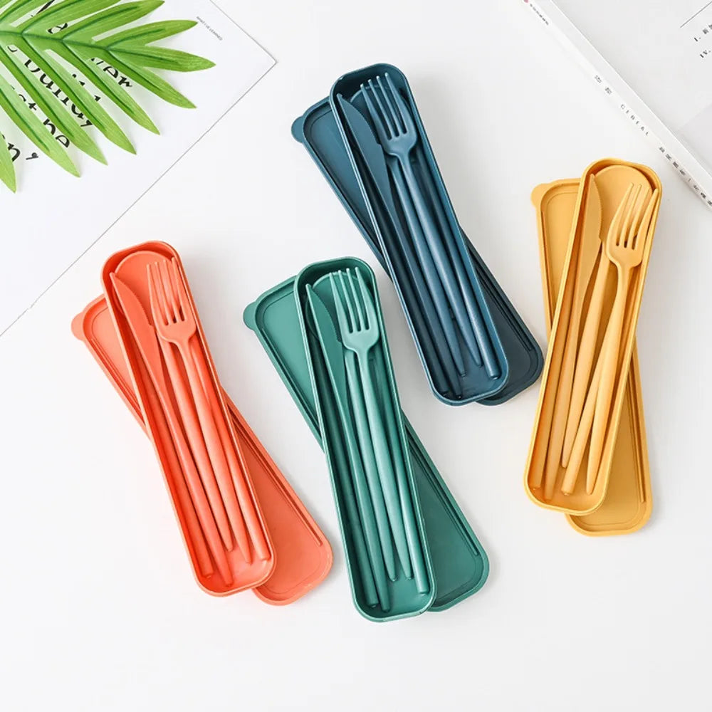 Set of colorful kawaii utensils in their cases on a white surface with green leaves.