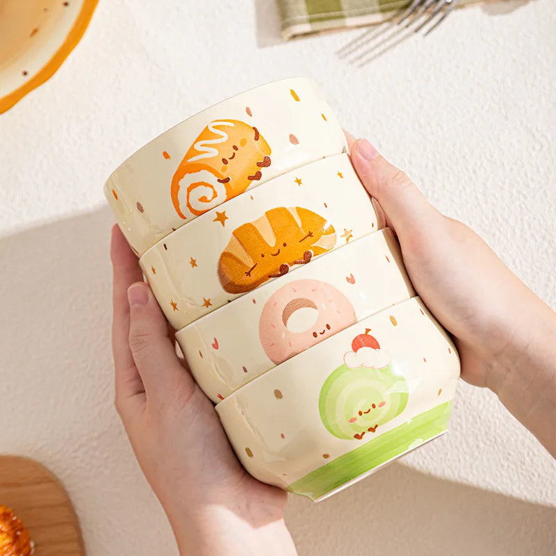 Four kawaii bowls with cartoon food on them being held by someone