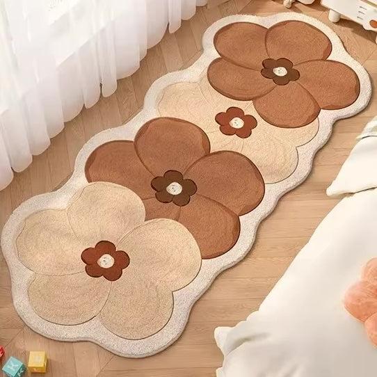 A rug with four flowers in brown and cream on a wooden floor.