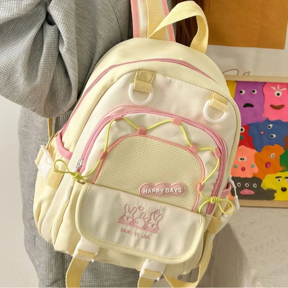 Small Kawaii backpack with pink accents worn by a person, against a neutral background.