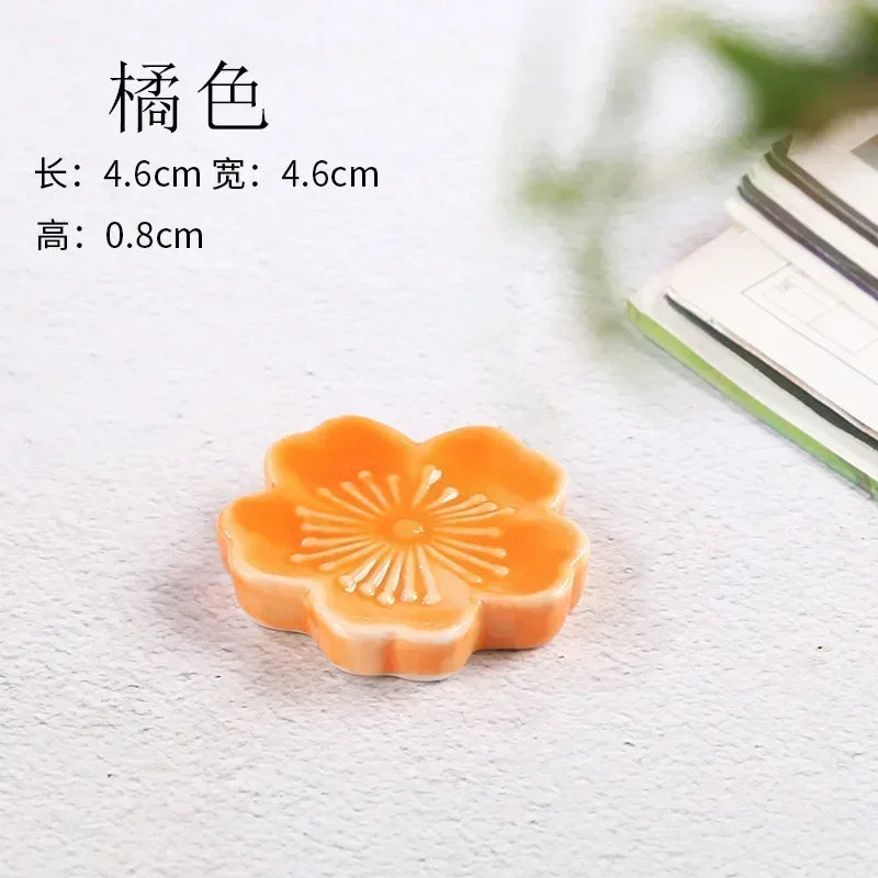 Orange flower-shaped kawaii chopstick holder on a textured white surface with text overlay.