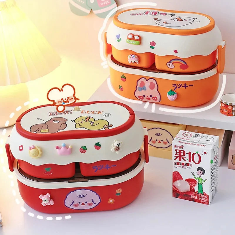 Two cartoon-themed kawaii bento boxes on a light surface with a box of juice in the background.