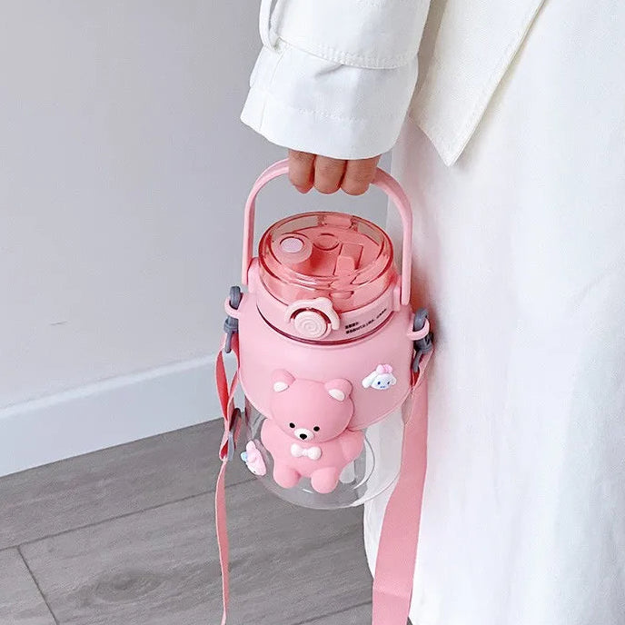 Pink kawaii water bottle with cartoon character and strap held by a person wearing a white coat.