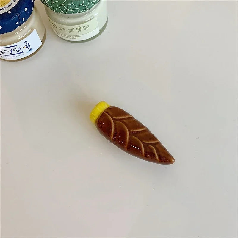 Carrot-shaped kawaii chopstick holder with a yellow top on a light gray surface