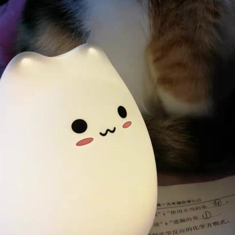 Cute kawaii animal-shaped night light on a surface with a cat's paw in the background