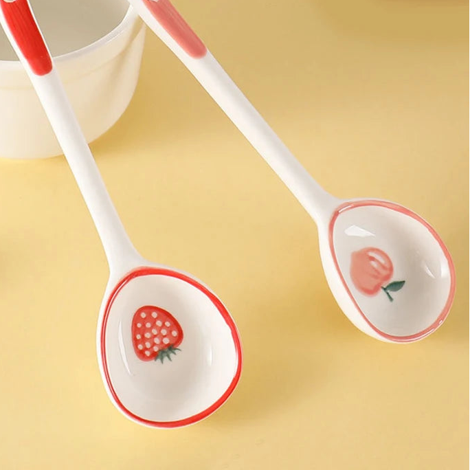 Two ceramic kawaii spoons with strawberry design on a yellow background