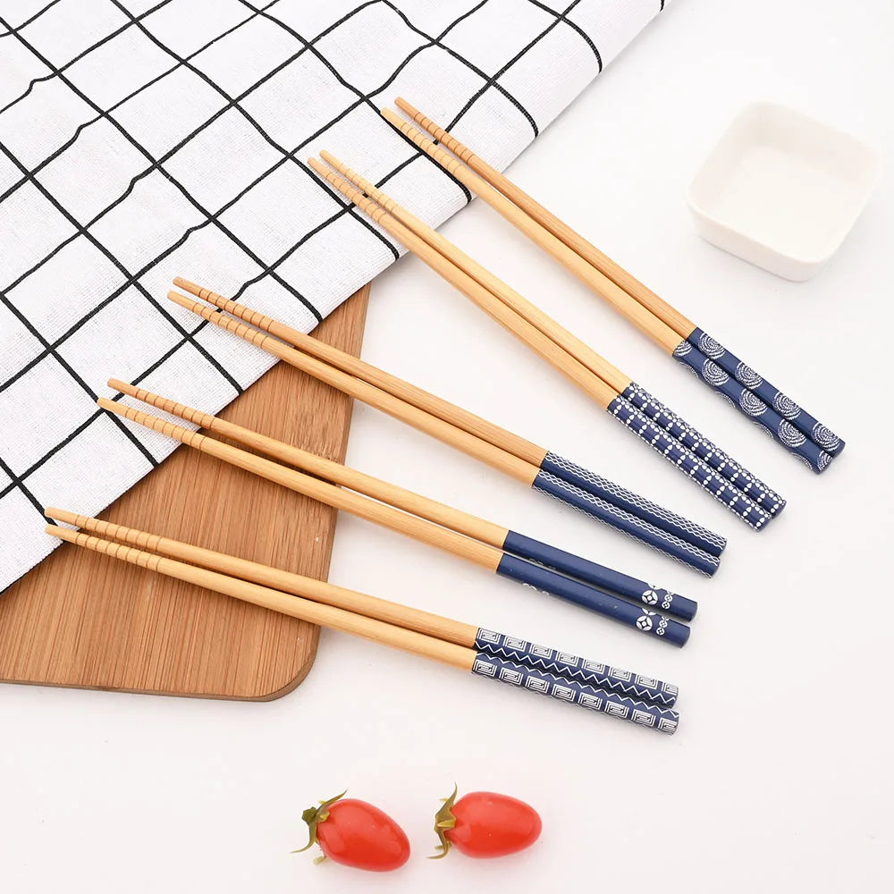 Set of wooden kawaii chopsticks with blue accents on a white surface with a grid pattern.