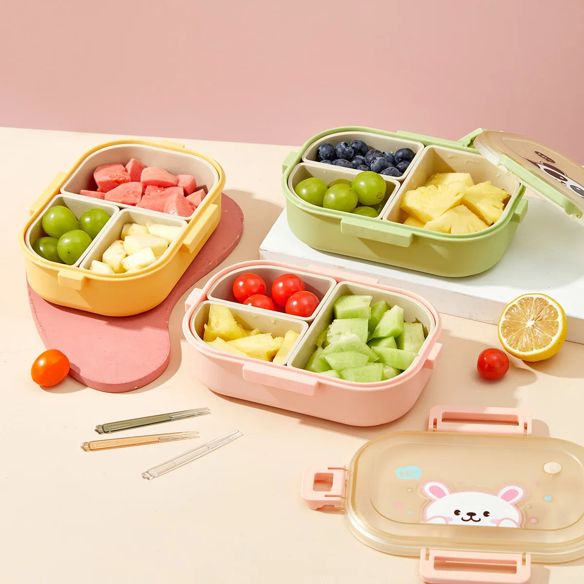 Set of kawaii colorful bento boxes with compartments filled with fruits and vegetables on a pink background.