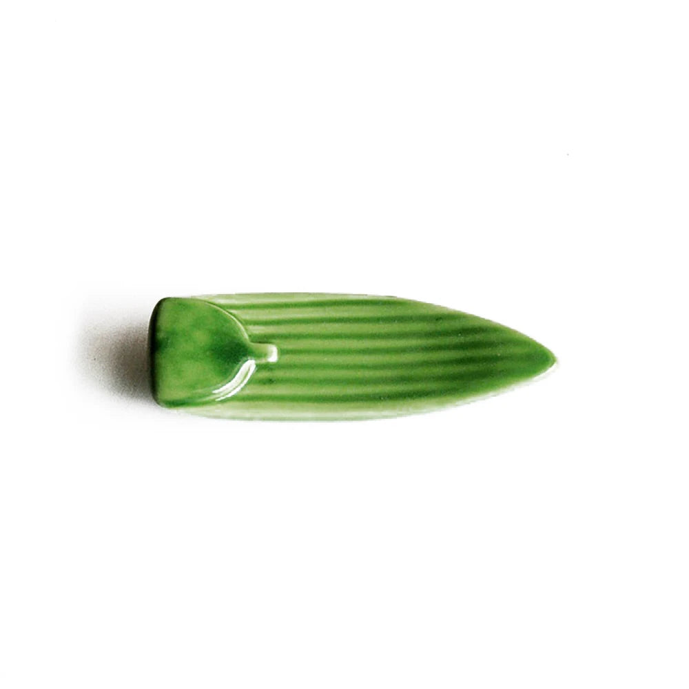 Green ceramic kawaii chopstick holders on a white background