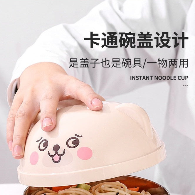 Hand holding a cartoon-themed instant noodle kawaii ramen bowl with visible text on a light gray background