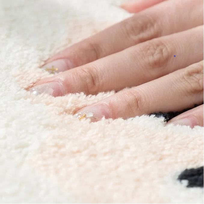 Close-up of a hand touching a soft, white kawaii rug
